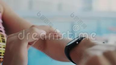 特写镜头。 女人用她的防水智能手表与触摸屏标记时间。 她为健身手环设置计时器